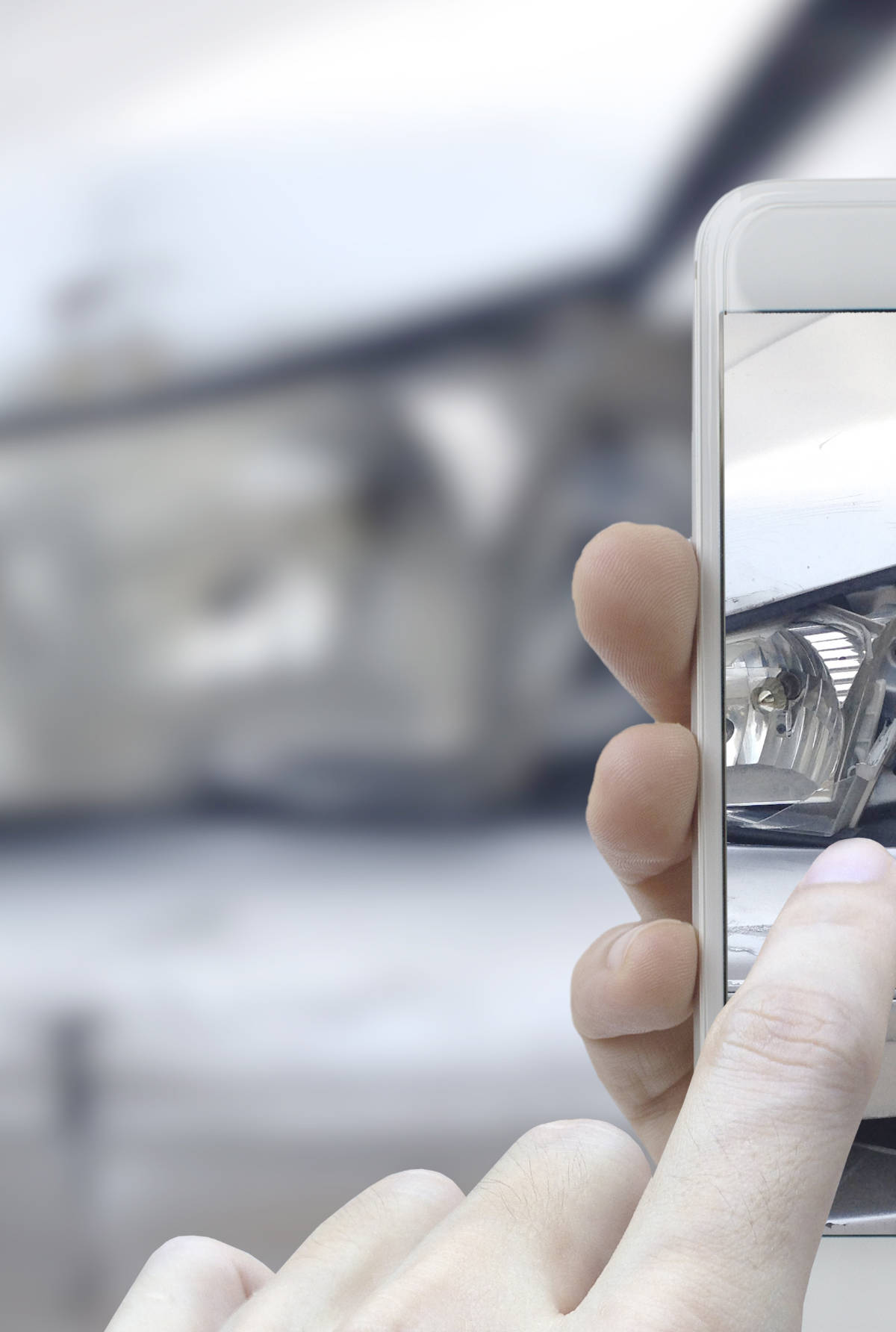 A hand holding a phone taking a picture of a car accident so it can be filed in an insurance claim